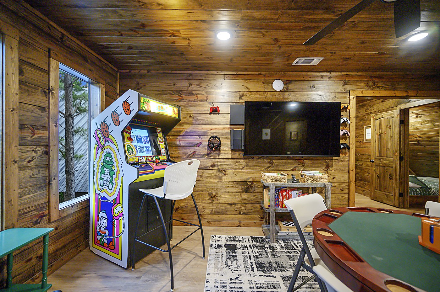 Game room with arcade machine, poker table, and big-screen TV